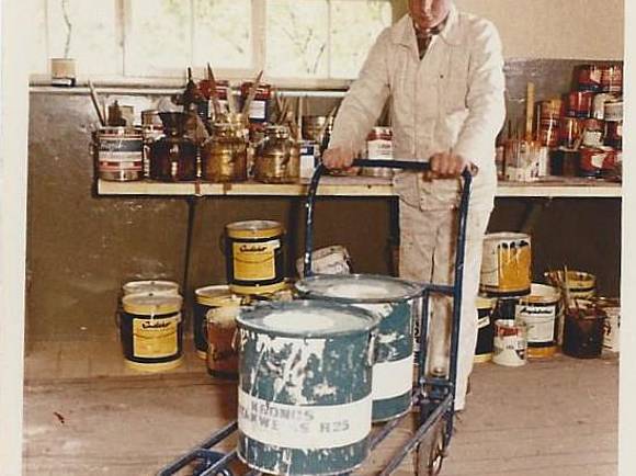 Eimer mit weißer Farbe werden mit dem Wagen zum Mischtisch gefahren